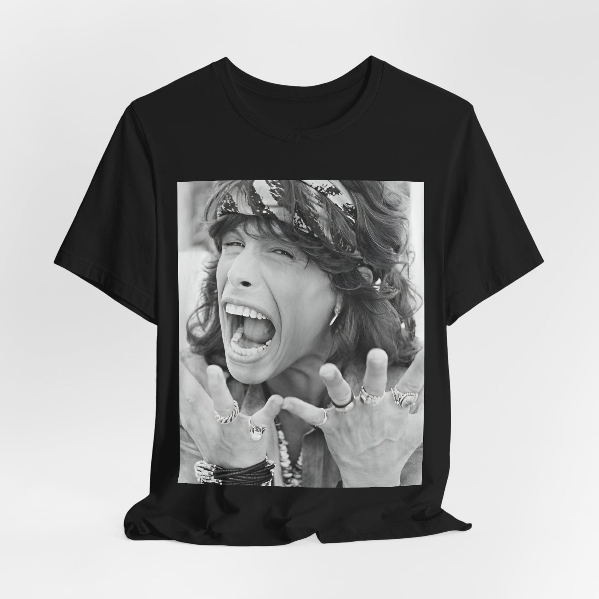 A black graphic t-shirt featuring a candid, dynamic photo of Aerosmith band members on tour in the 1970s, possibly showing action or interaction on stage or backstage.