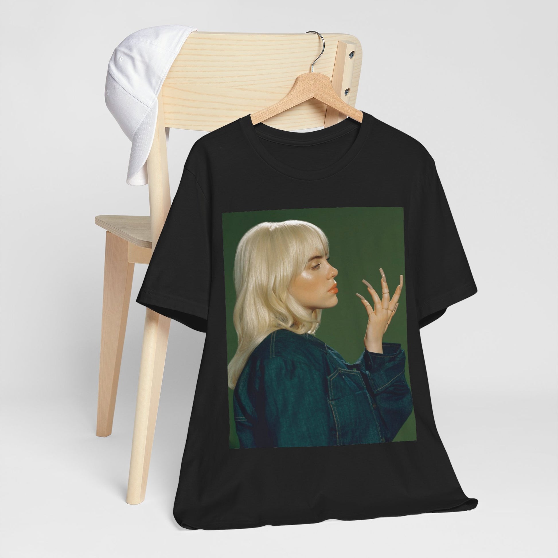 A vintage-style portrait of Billie Eilish with platinum blonde hair and long nails, wearing a denim jacket against a green background.