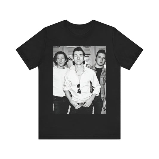 A black graphic t-shirt featuring a vintage-style design related to Arctic Monkeys' 'AM' album era, possibly with the album art or band imagery.