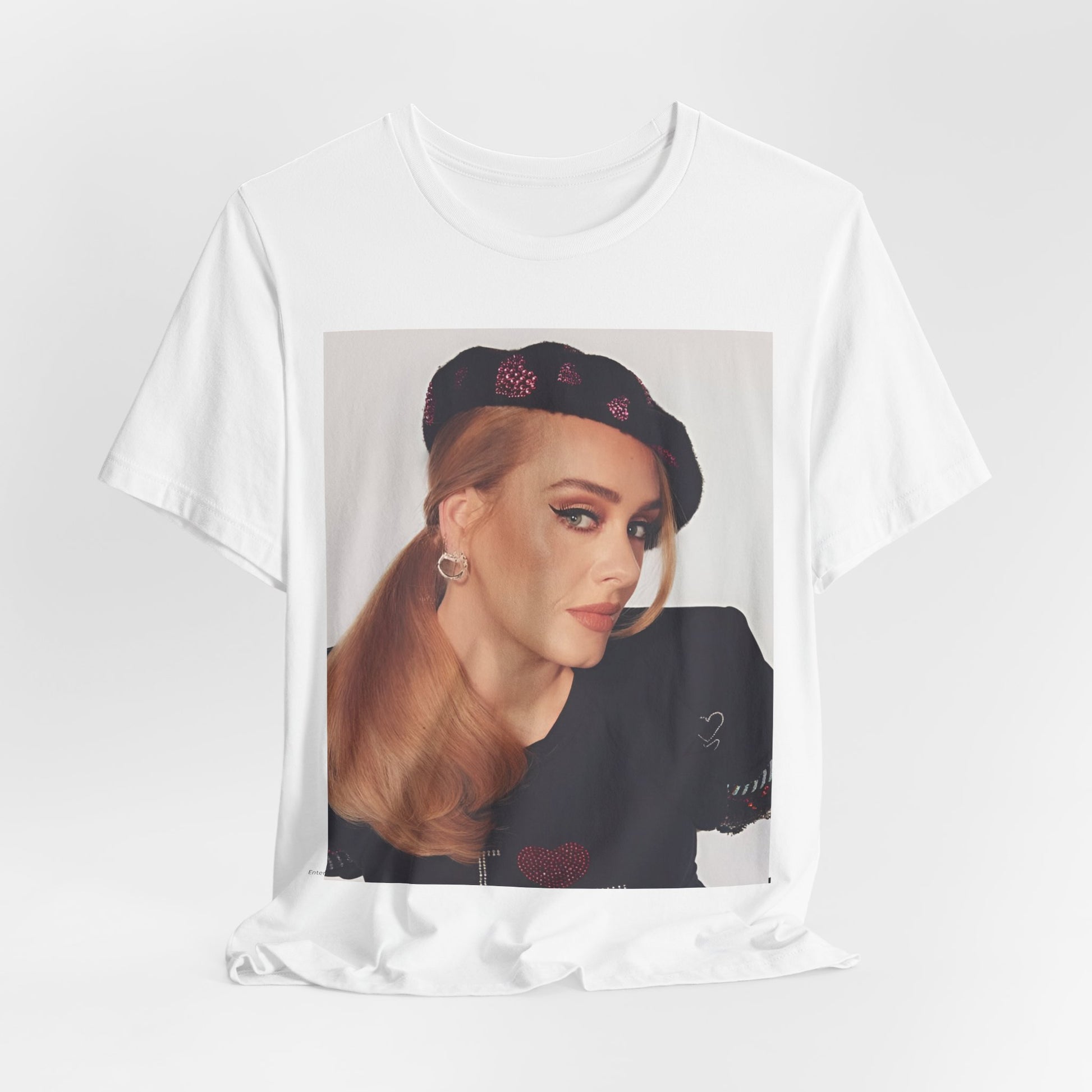 A black graphic t-shirt featuring a black and white photo of Adele wearing a heart-shaped beret, with a gentle or smiling expression.