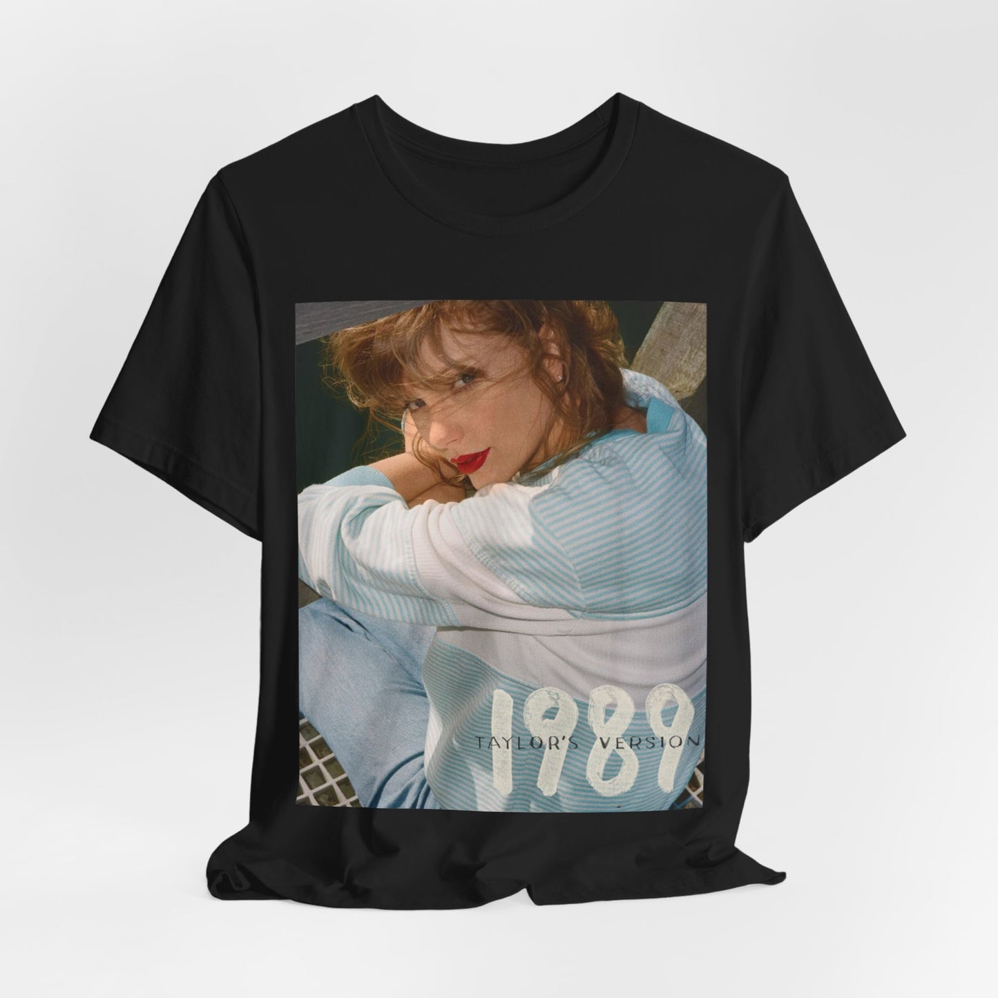 A black graphic t-shirt featuring a 1989 aesthetic graphic of Taylor Swift.