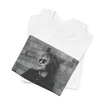 A black graphic t-shirt featuring a vintage graphic related to Elton John's 'Farewell Yellow Brick Road' tour.