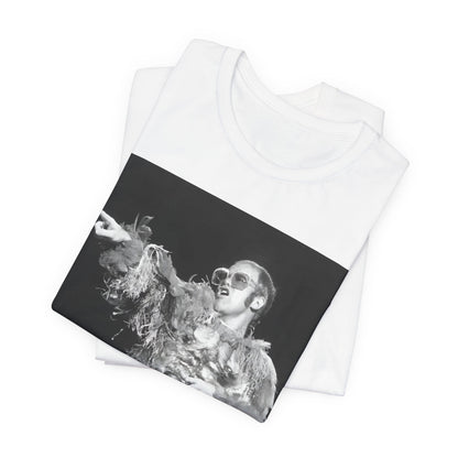 A black graphic t-shirt featuring a retro graphic of Elton John as a rock legend performing live.