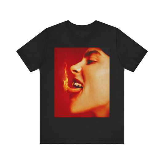 A close-up, red-toned photo of a face in profile with its mouth open and a live flame on the tongue, printed on a graphic t-shirt.