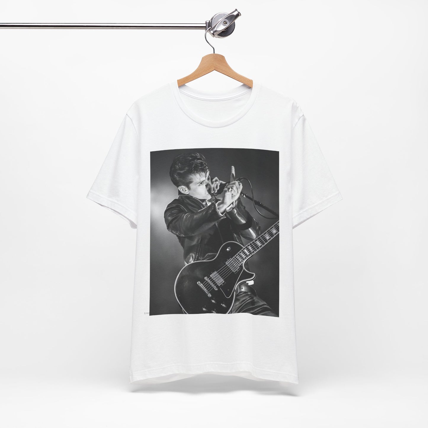 A black graphic t-shirt featuring a dynamic black and white graphic or photo of Arctic Monkeys performing live, emphasizing energy.
