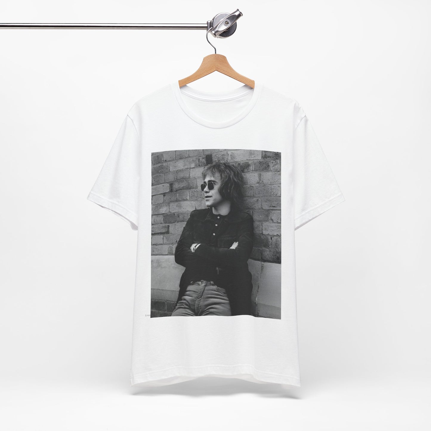 A black graphic t-shirt featuring a vintage graphic related to Elton John's 'Farewell Yellow Brick Road' tour.