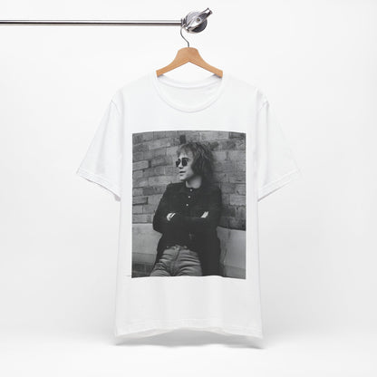A black graphic t-shirt featuring a vintage graphic related to Elton John's 'Farewell Yellow Brick Road' tour.