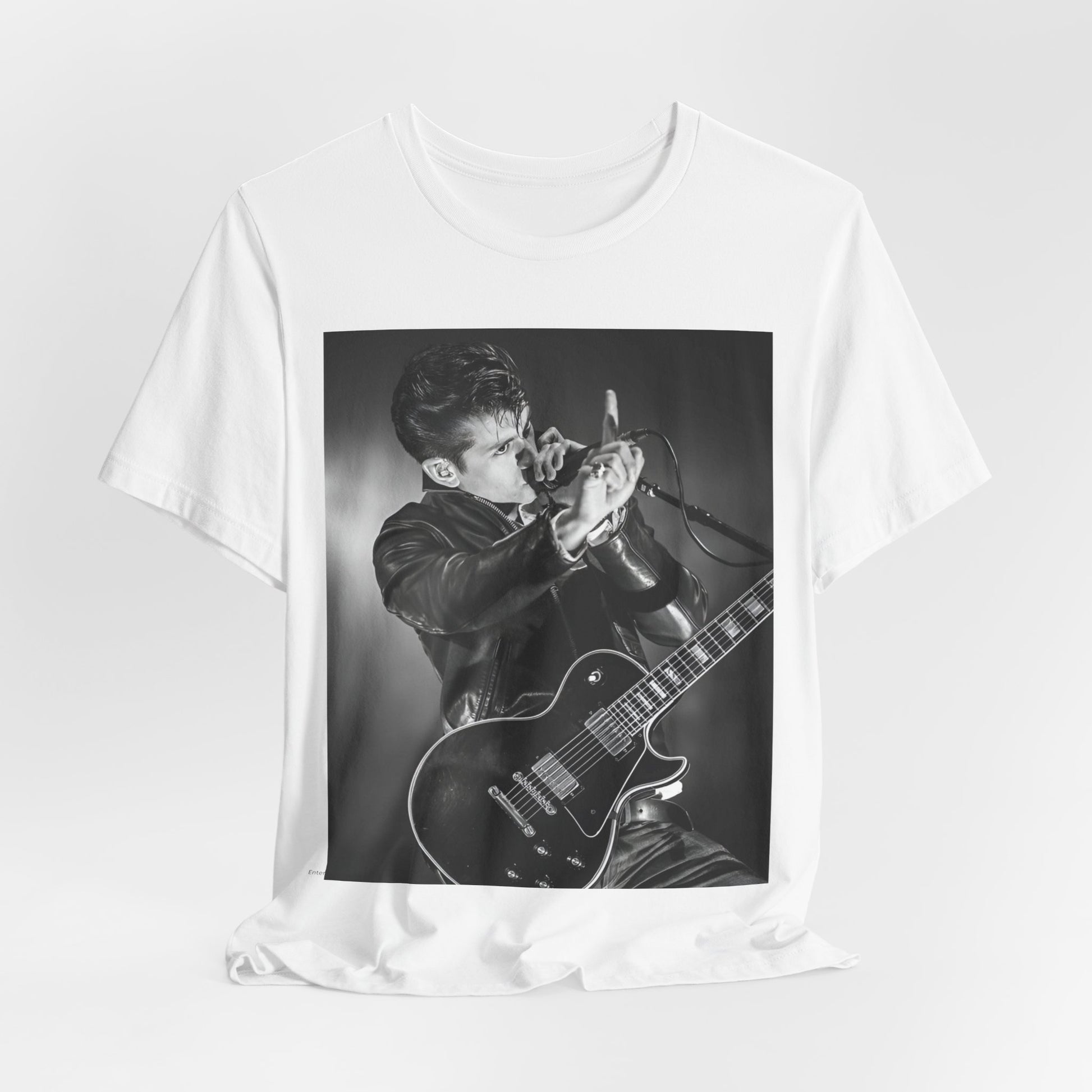 A black graphic t-shirt featuring a dynamic black and white graphic or photo of Arctic Monkeys performing live, emphasizing energy.
