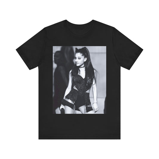 A black graphic t-shirt featuring a graphic inspired by Ariana Grande's 'Dangerous Woman' album or era, possibly with her iconic mask or pose.