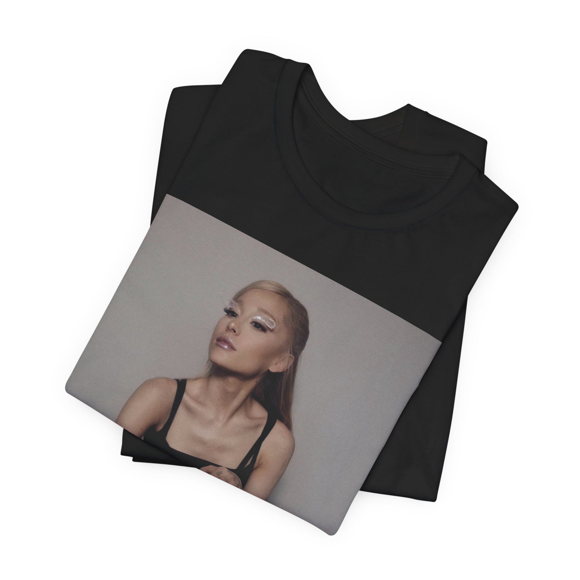A black graphic t-shirt featuring a bold and beautiful graphic of Ariana Grande, emphasizing her strong and confident presence.