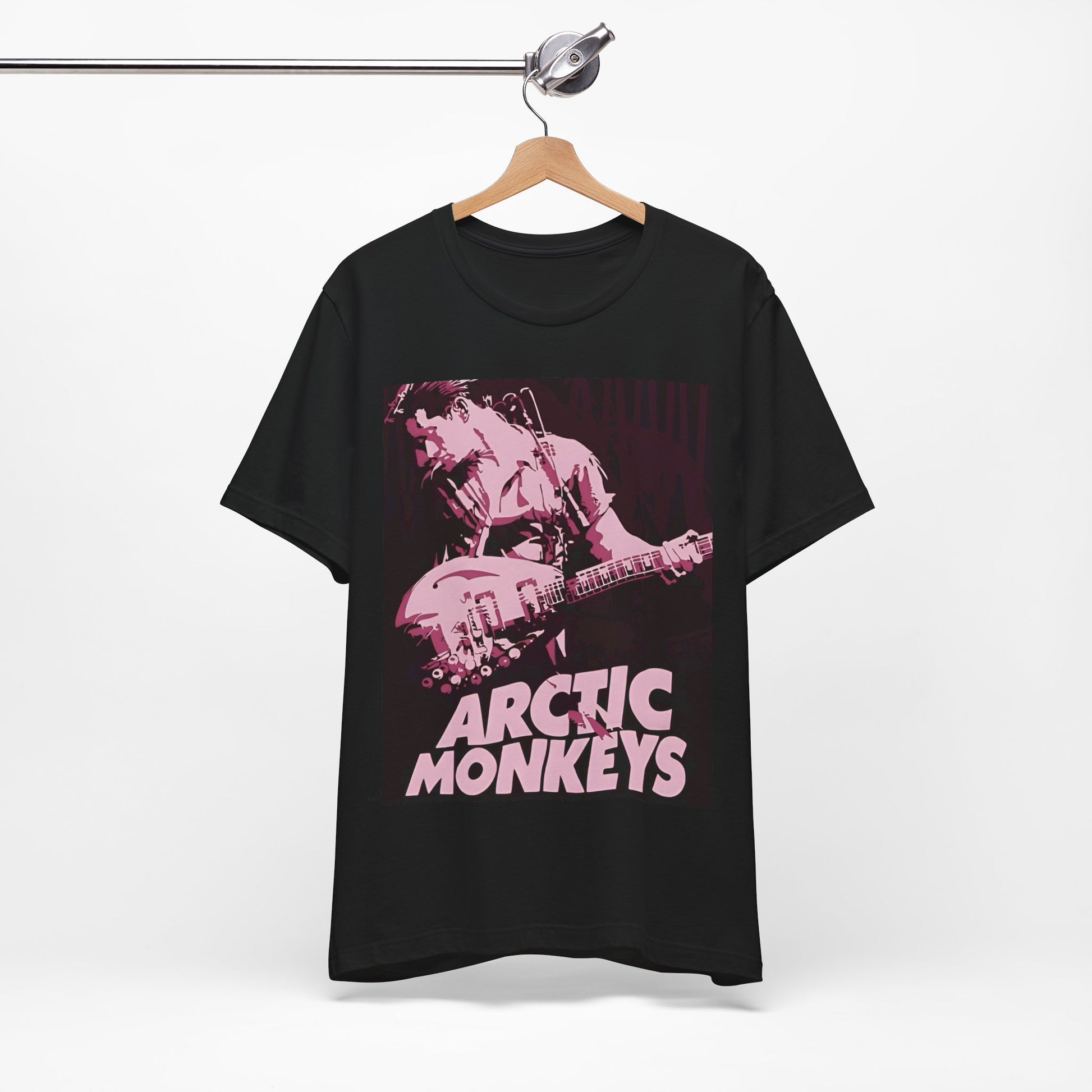 A black graphic t-shirt featuring the Arctic Monkeys logo in a prominent pink color, creating an aesthetic look.