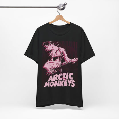 A black graphic t-shirt featuring the Arctic Monkeys logo in a prominent pink color, creating an aesthetic look.