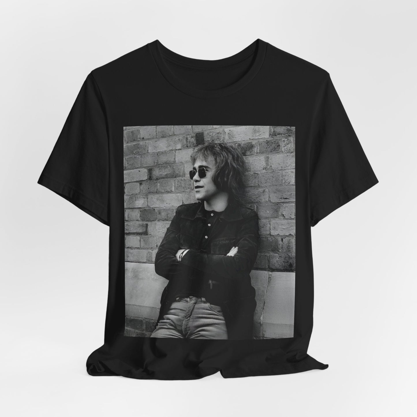 A black graphic t-shirt featuring a vintage graphic related to Elton John's 'Farewell Yellow Brick Road' tour.