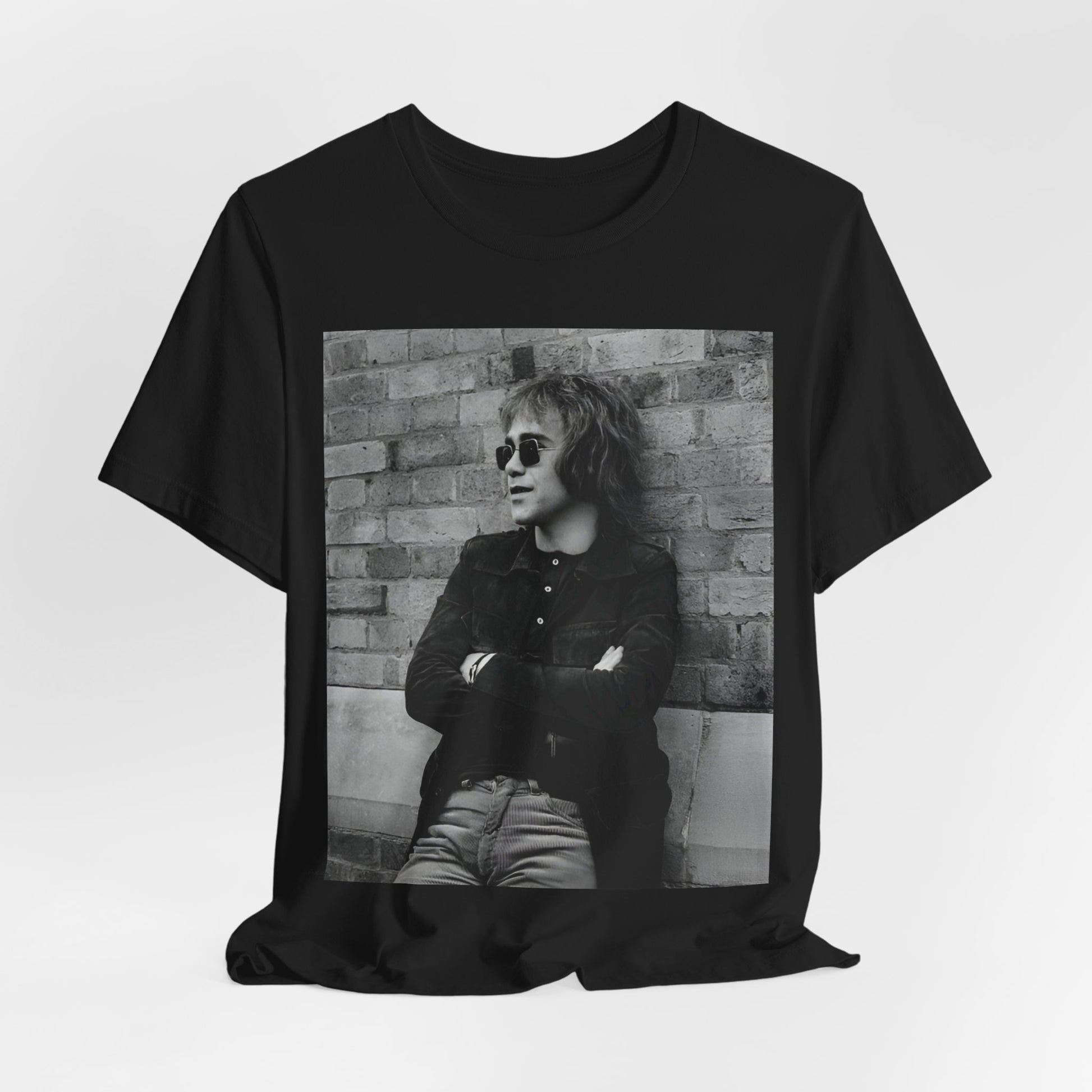 A black graphic t-shirt featuring a vintage graphic related to Elton John's 'Farewell Yellow Brick Road' tour.