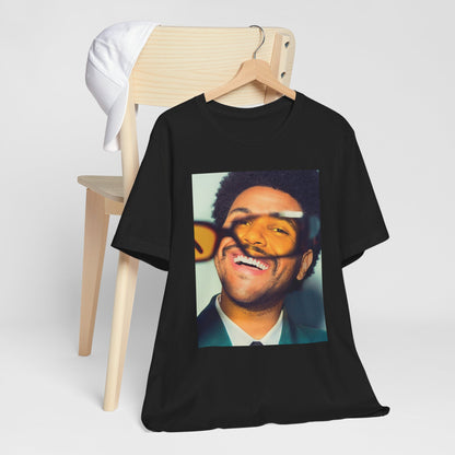 A black graphic t-shirt featuring a bold graphic of The Weeknd as a pop superstar.