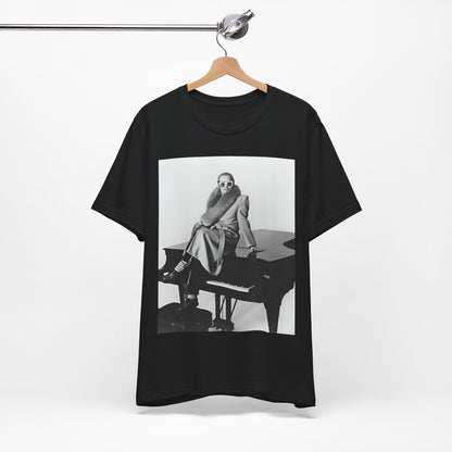 A black graphic t-shirt featuring a black and white photo of Elton John playing the piano.