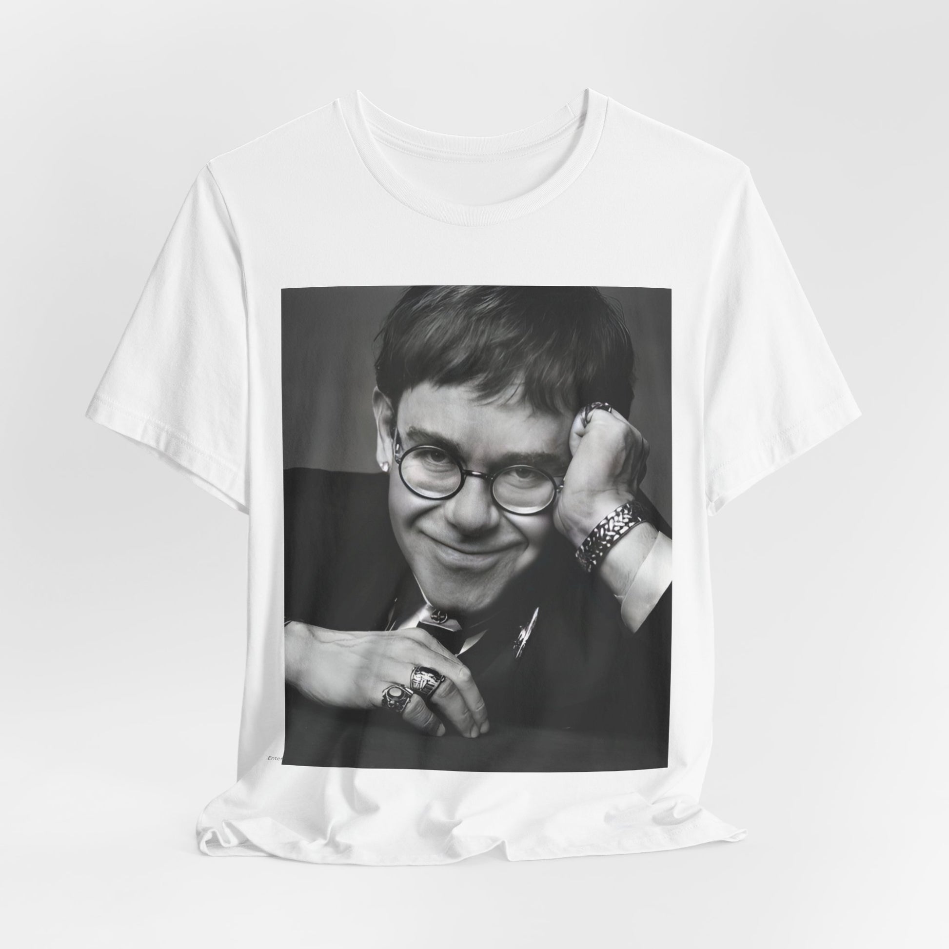 A black graphic t-shirt featuring a retro black and white photo portrait of Elton John.