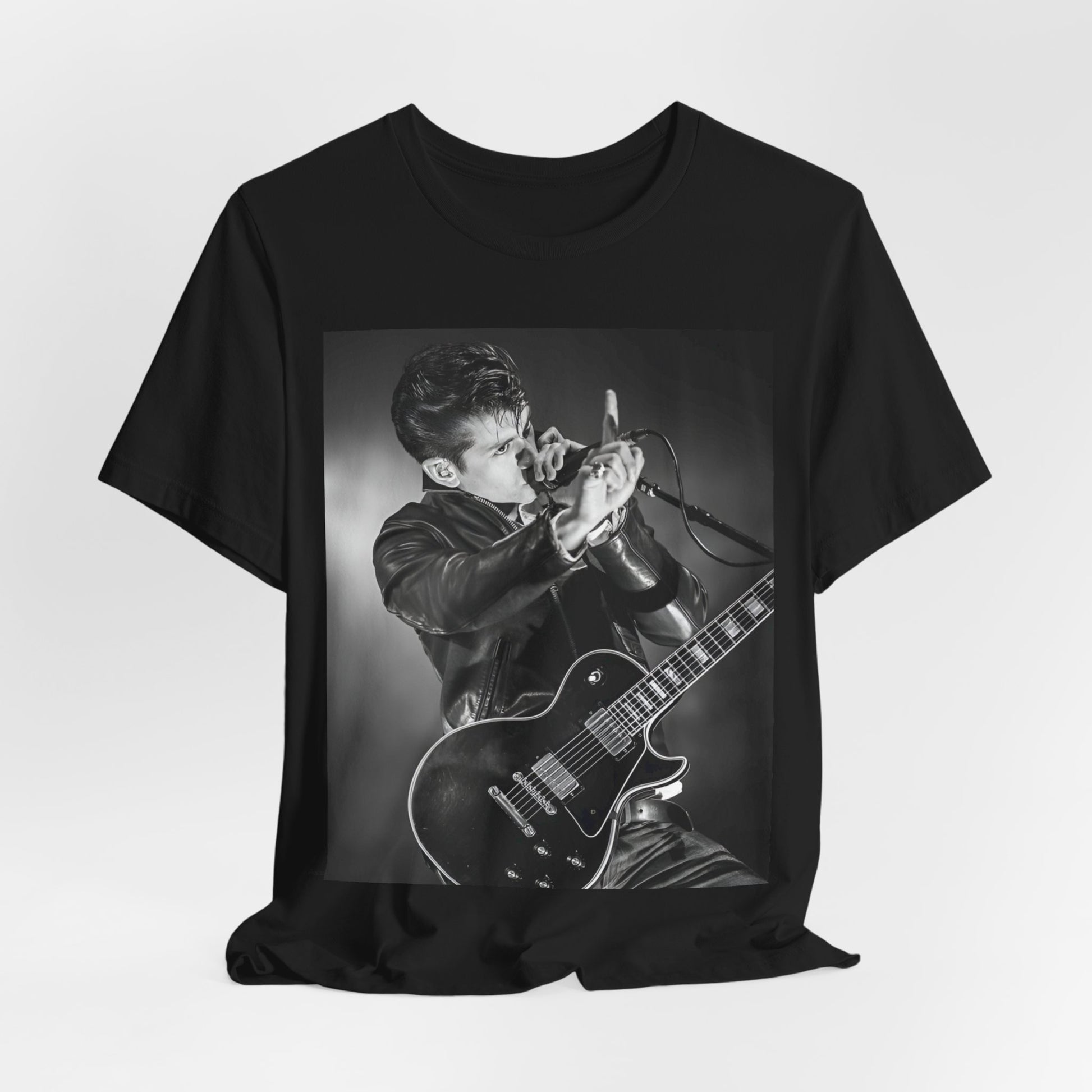 A black graphic t-shirt featuring a dynamic black and white graphic or photo of Arctic Monkeys performing live, emphasizing energy.