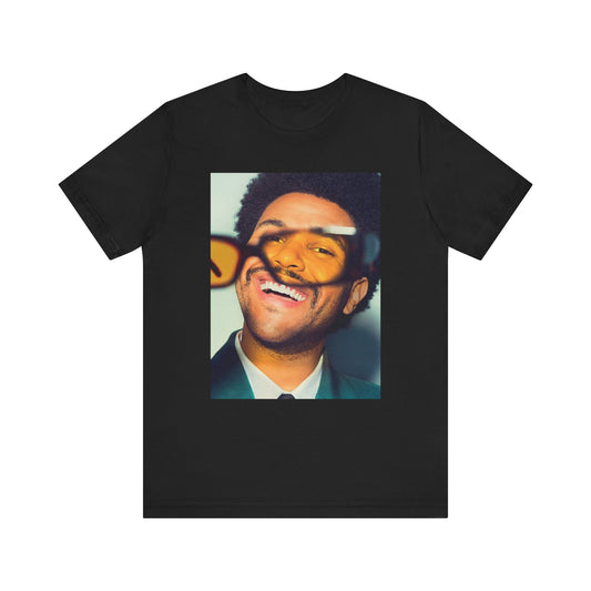 A black graphic t-shirt featuring a bold graphic of The Weeknd as a pop superstar.