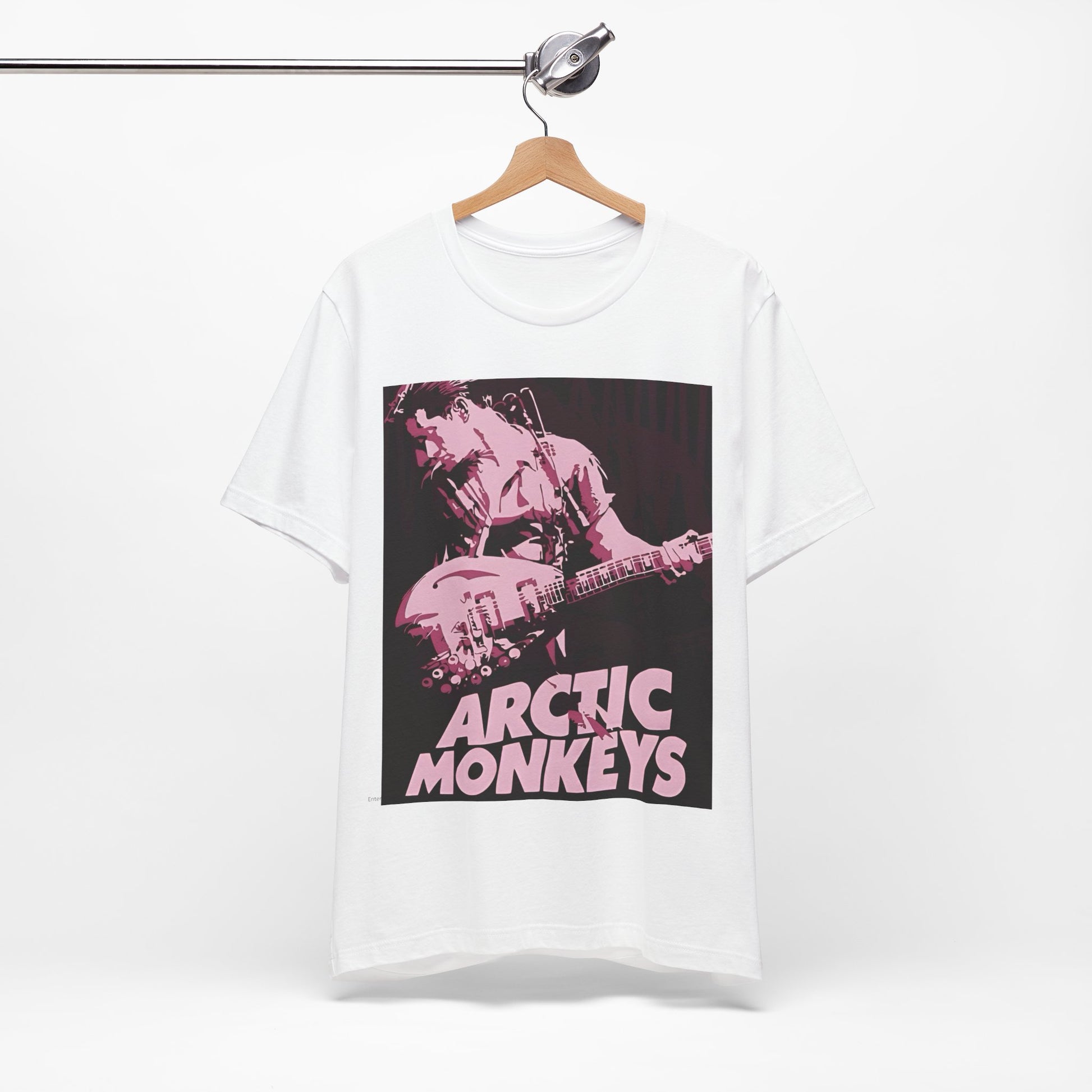 A black graphic t-shirt featuring the Arctic Monkeys logo in a prominent pink color, creating an aesthetic look.