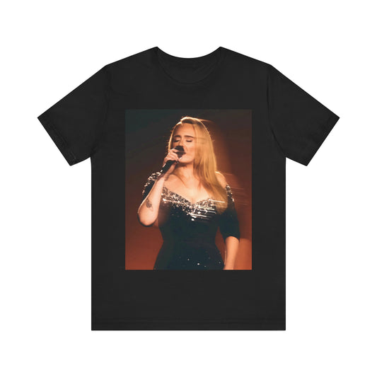 A black graphic t-shirt featuring a stylized image or photo of Adele related to her Las Vegas residency, possibly with elements of stage lighting or show branding.