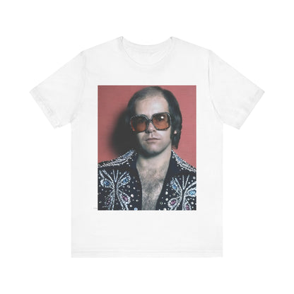 A black graphic t-shirt featuring a vintage glam rock icon graphic of Elton John.