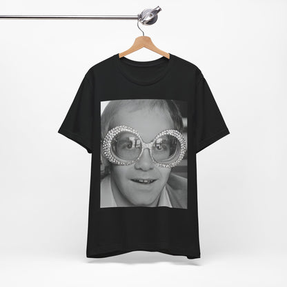 A black graphic t-shirt featuring a graphic of Elton John emphasizing his iconic glasses and fashion.