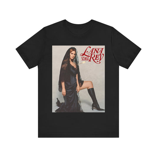 Lana Del Rey kneeling in a black dress and a black lace veil while holding a lit match, printed on a graphic t-shirt.