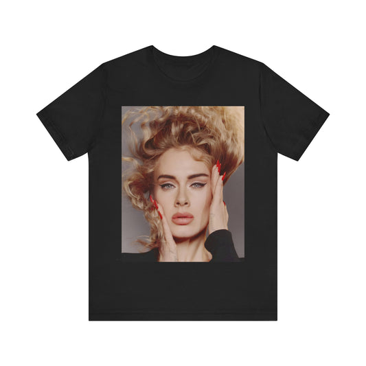 A black graphic t-shirt featuring a detailed, artistic black and white portrait of Adele with her hair dramatically caught in a breeze around her face and her hands gently placed on her cheeks.