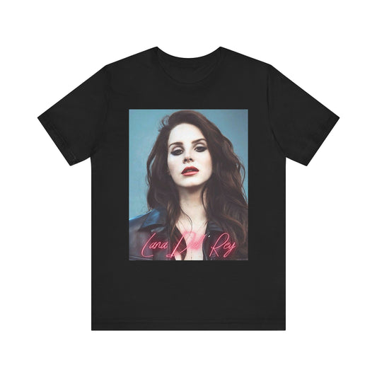 A moody portrait of Lana Del Rey in a leather jacket with her name written across it in a pink neon script, printed on a t-shirt.