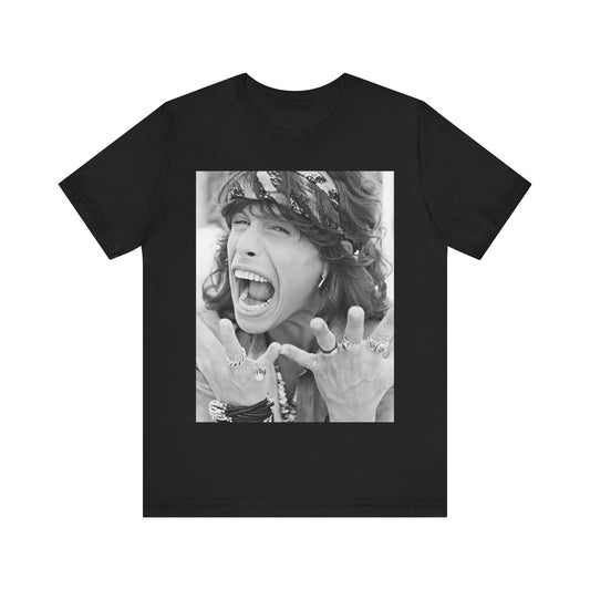 A black graphic t-shirt featuring a candid, dynamic photo of Aerosmith band members on tour in the 1970s, possibly showing action or interaction on stage or backstage.