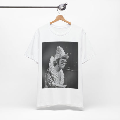 A black graphic t-shirt featuring a 70s pop aesthetic graphic of Elton John.