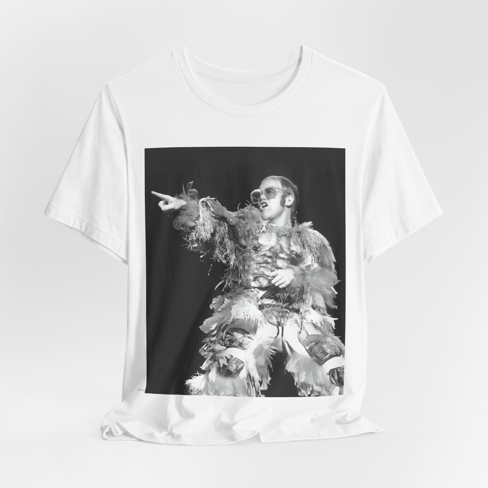 A black graphic t-shirt featuring a retro graphic of Elton John as a rock legend performing live.