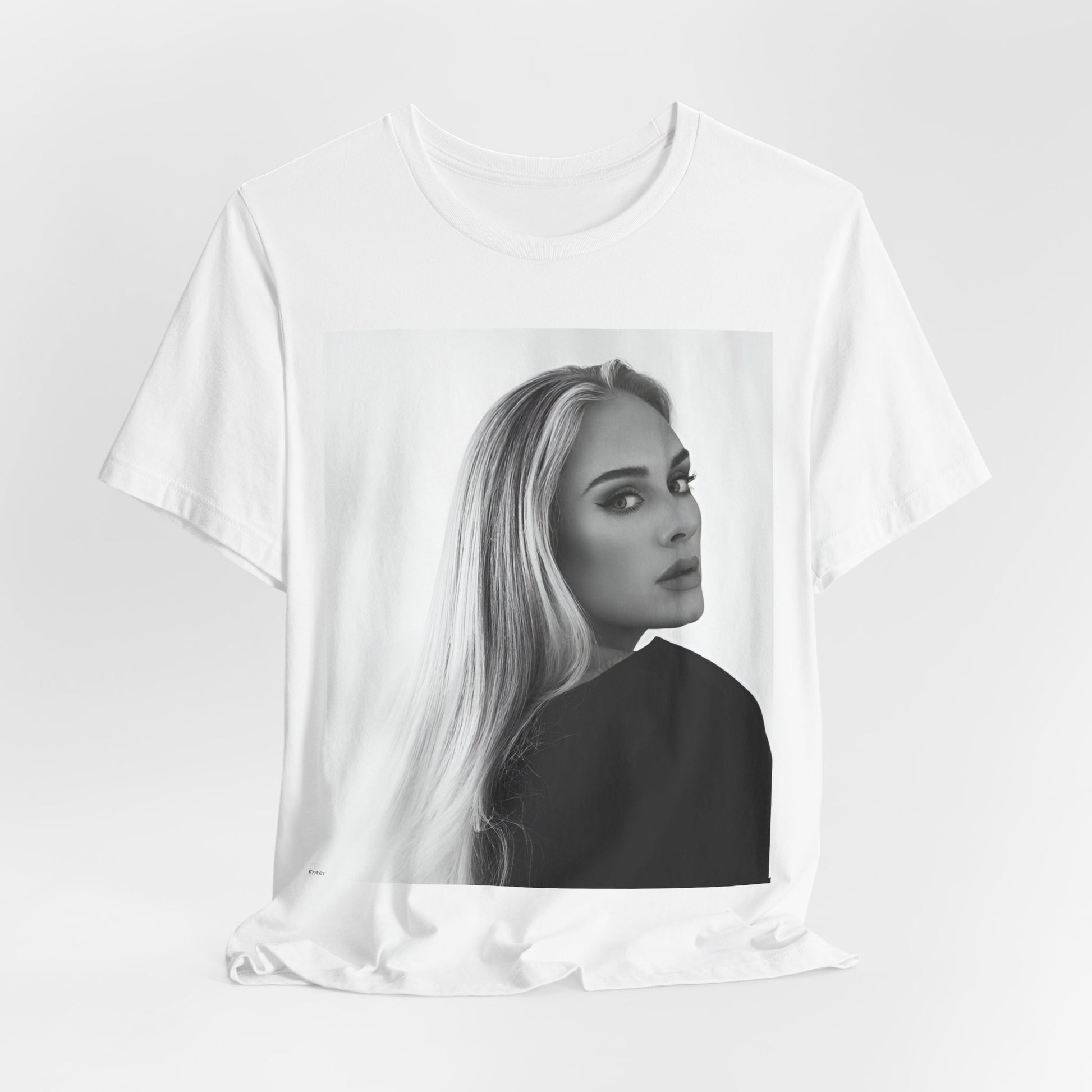 A black graphic t-shirt featuring a black and white, monochromatic portrait of Adele, showing her with a serene or thoughtful expression.