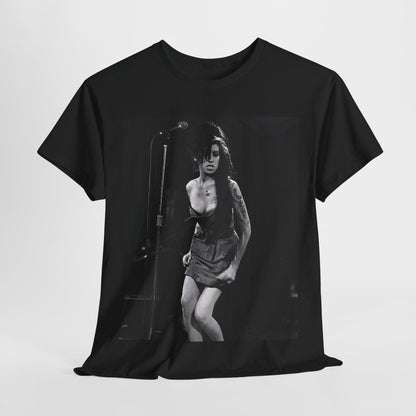 A black graphic t-shirt featuring a photo of Amy Winehouse performing live on stage at nightfall, with stage lighting effects.
