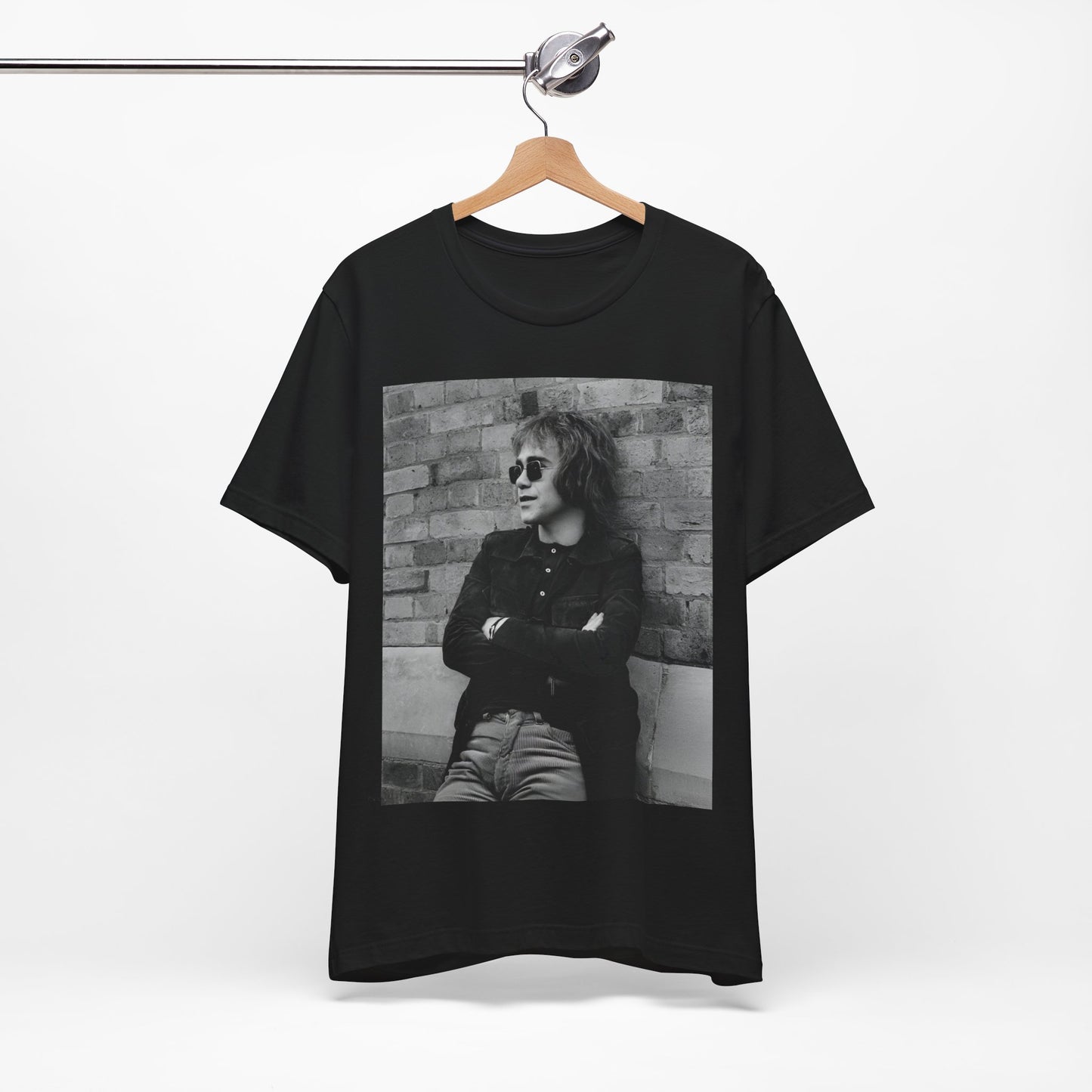 A black graphic t-shirt featuring a vintage graphic related to Elton John's 'Farewell Yellow Brick Road' tour.