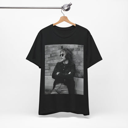 A black graphic t-shirt featuring a vintage graphic related to Elton John's 'Farewell Yellow Brick Road' tour.