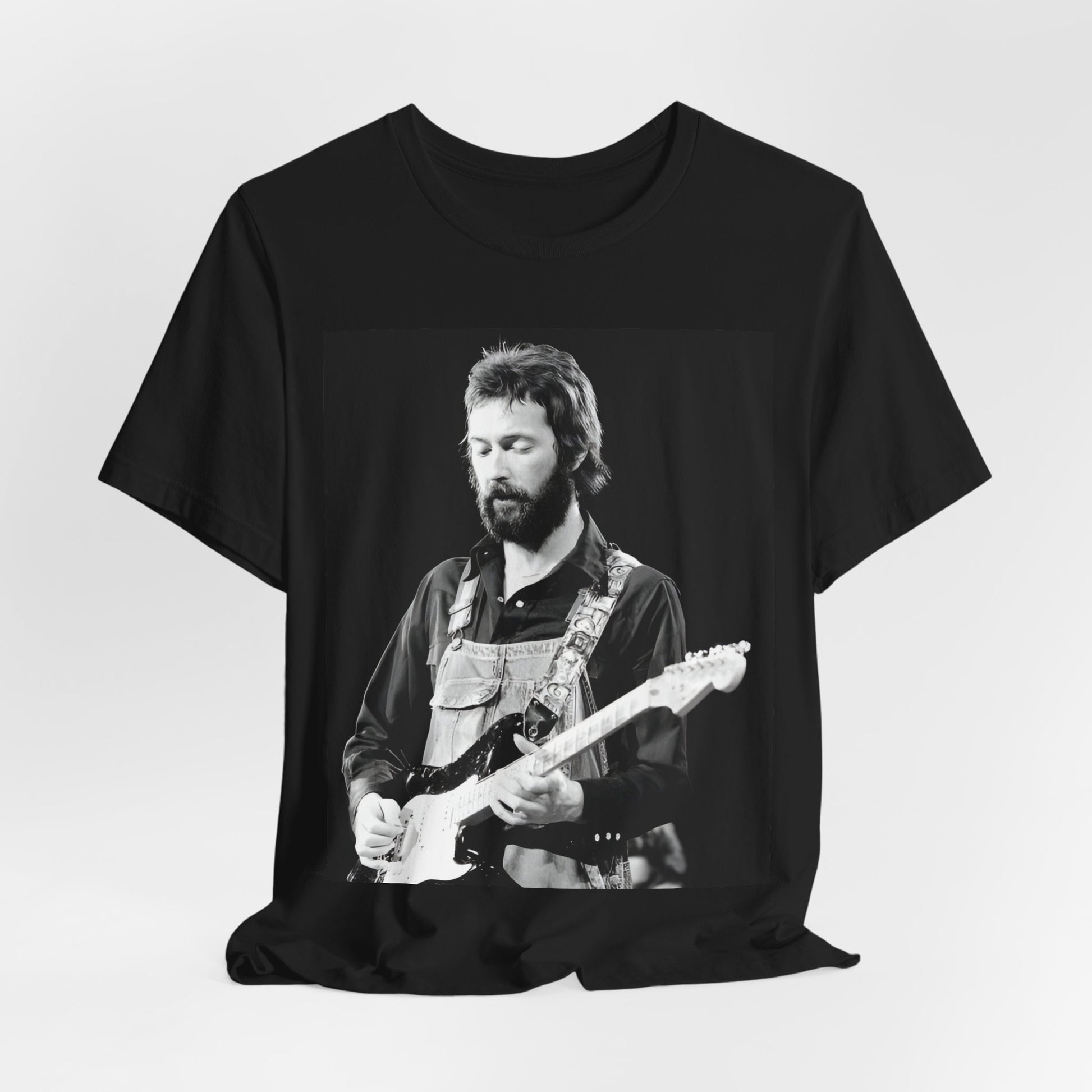 A black graphic t-shirt featuring a graphic or photo of Eric Clapton performing live on stage with his guitar.