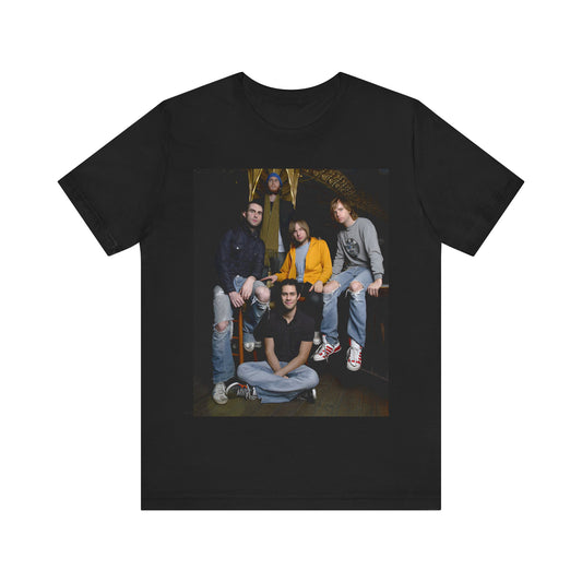 A high-energy, colorful photo of Maroon 5 performing live on stage at a concert, printed on a graphic t-shirt.