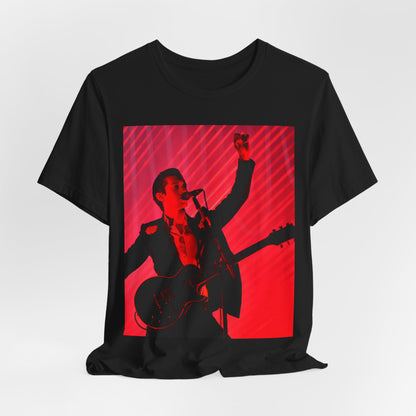 A black graphic t-shirt featuring a dynamic graphic or photo of Arctic Monkeys performing live in concert.