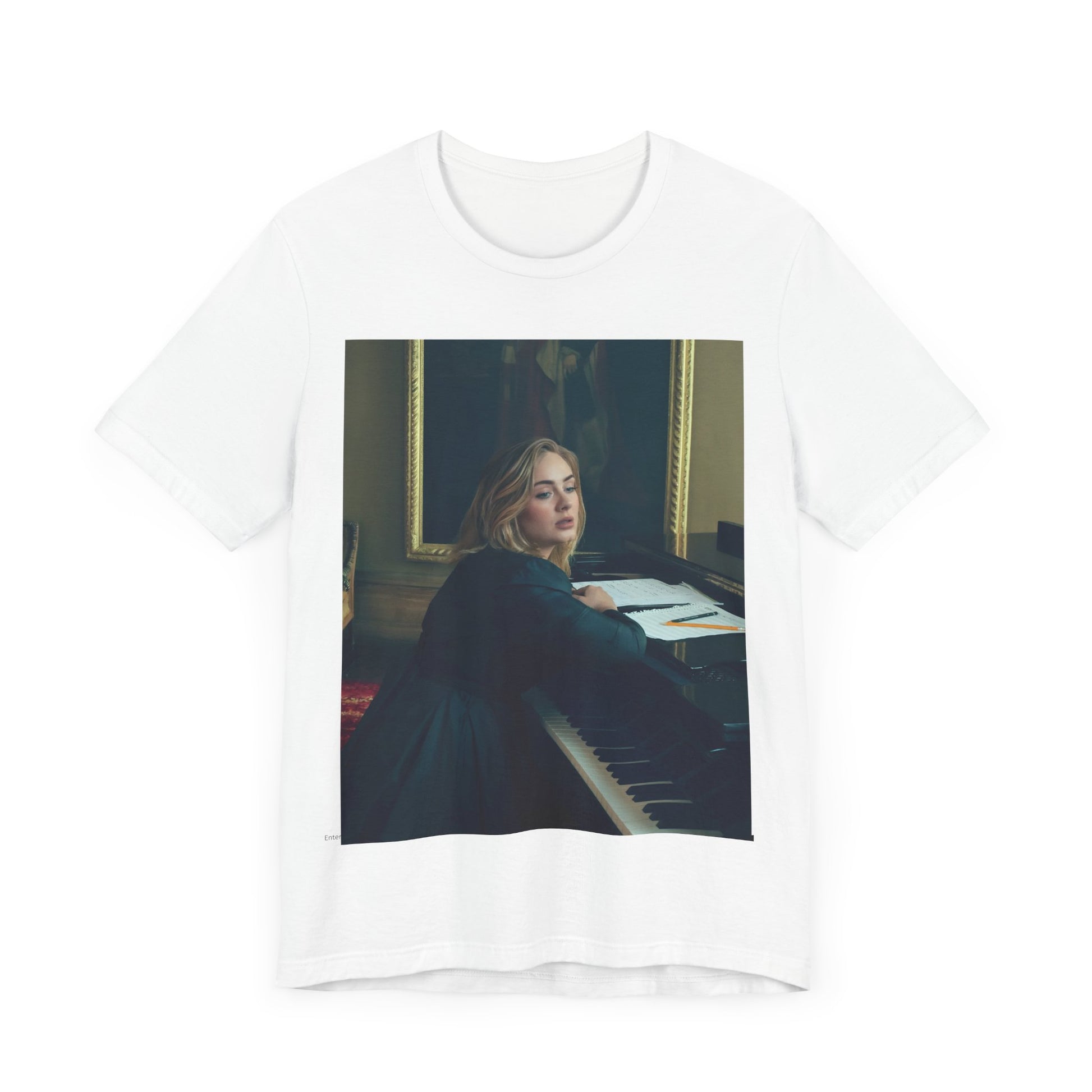 A black graphic t-shirt featuring a black and white photo of Adele sitting at a piano, with a focused and emotional expression as if performing.