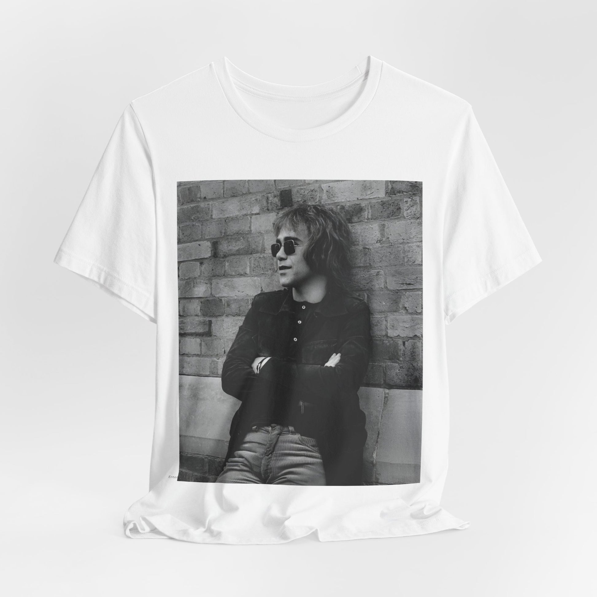 A black graphic t-shirt featuring a vintage graphic related to Elton John's 'Farewell Yellow Brick Road' tour.