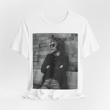 A black graphic t-shirt featuring a vintage graphic related to Elton John's 'Farewell Yellow Brick Road' tour.