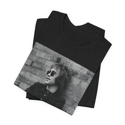 A black graphic t-shirt featuring a vintage graphic related to Elton John's 'Farewell Yellow Brick Road' tour.