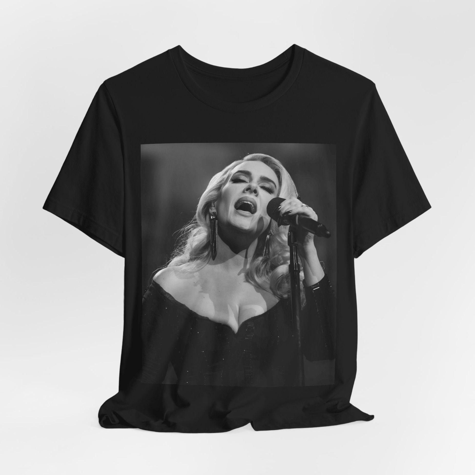A black graphic t-shirt featuring a dynamic image of Adele performing on stage, with lighting effects, likely from her 'One Night Only' concert special.