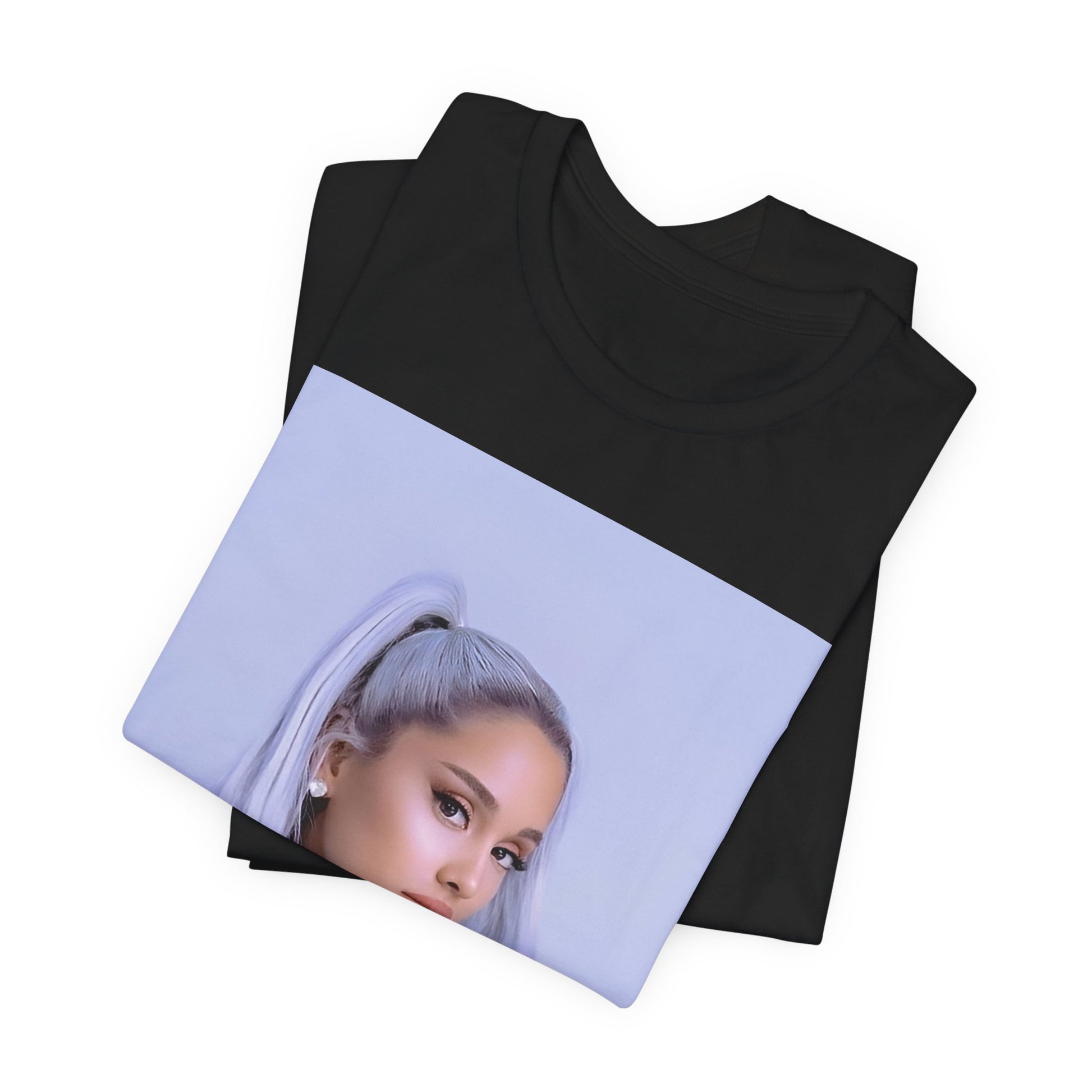 A black graphic t-shirt featuring a stylized graphic of Ariana Grande, possibly with a crown or 'Pop Queen' text, emphasizing her iconic status.