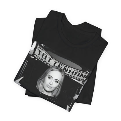 A black graphic t-shirt featuring a photo of Adele in a casual setting, surrounded by fans at a Tottenham event, showing her smiling or interacting.