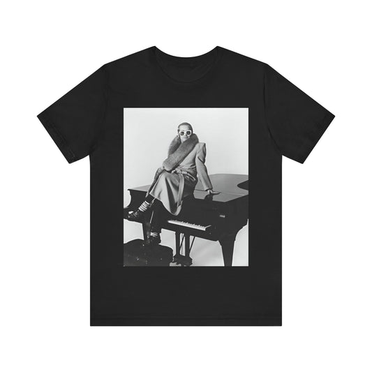 A black graphic t-shirt featuring a black and white photo of Elton John playing the piano.