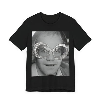 A black graphic t-shirt featuring a graphic of Elton John emphasizing his iconic glasses and fashion.