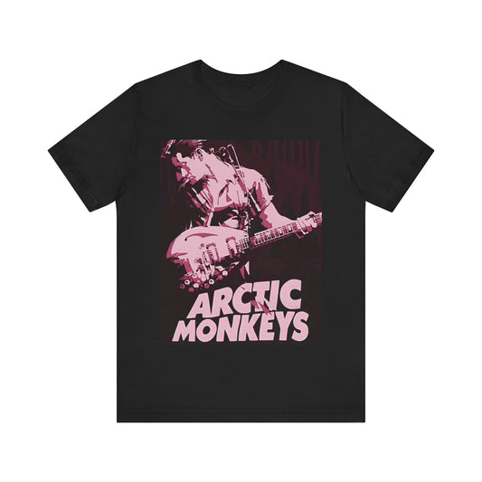 A black graphic t-shirt featuring the Arctic Monkeys logo in a prominent pink color, creating an aesthetic look.